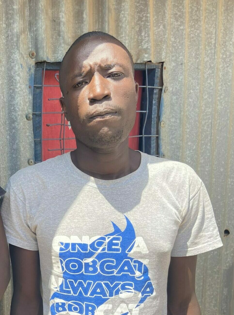 Photo of Mohammed in front of corrugated steel wall