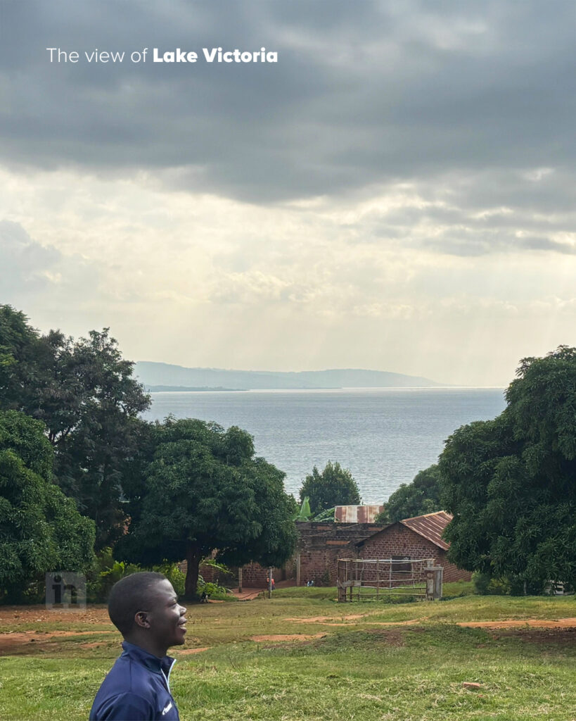 Lake Victoria is visible through the green trees, with rays of sunshine coming like ribbons through the clouds over the big lake.