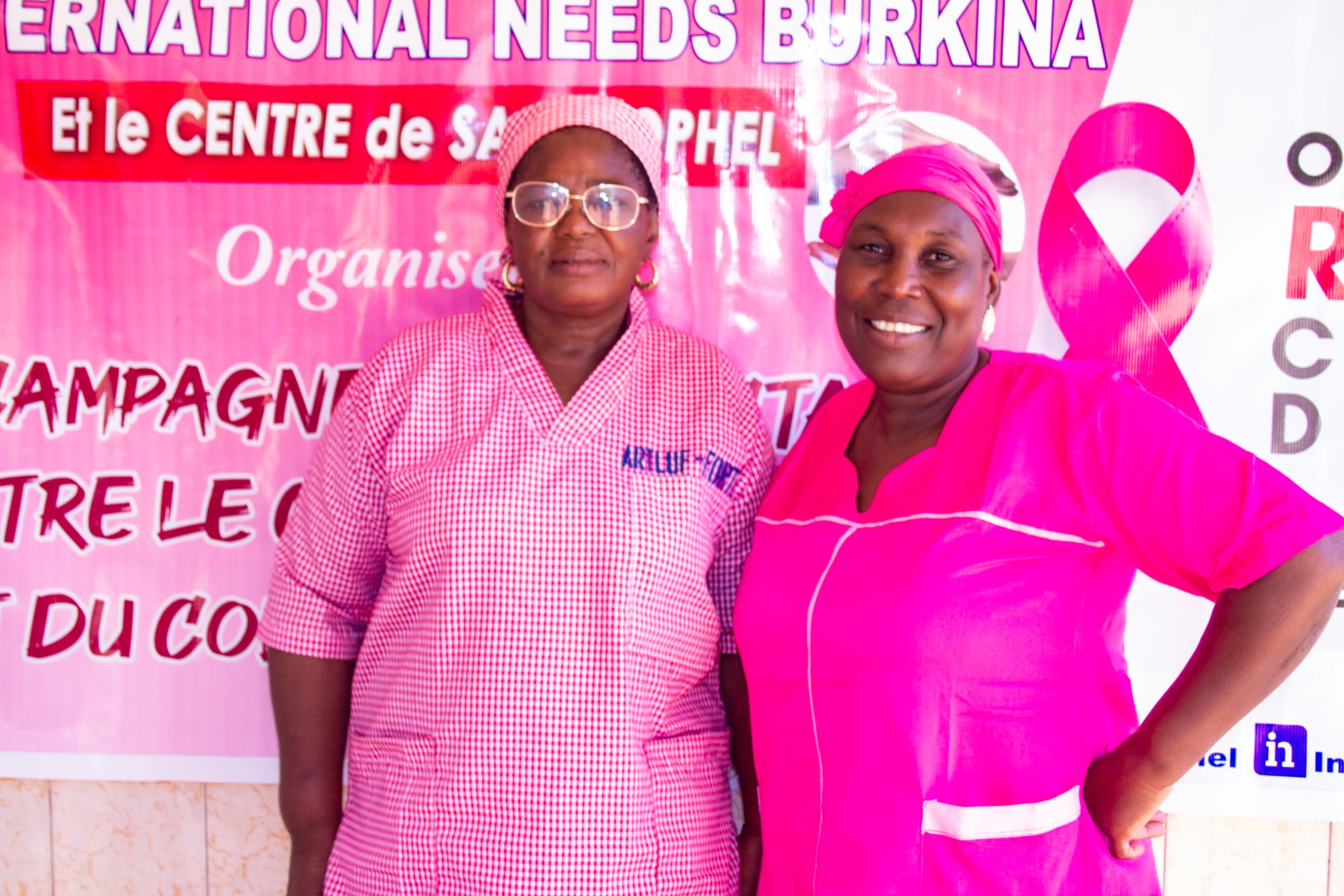 two midwives stand in front of the pink october sign