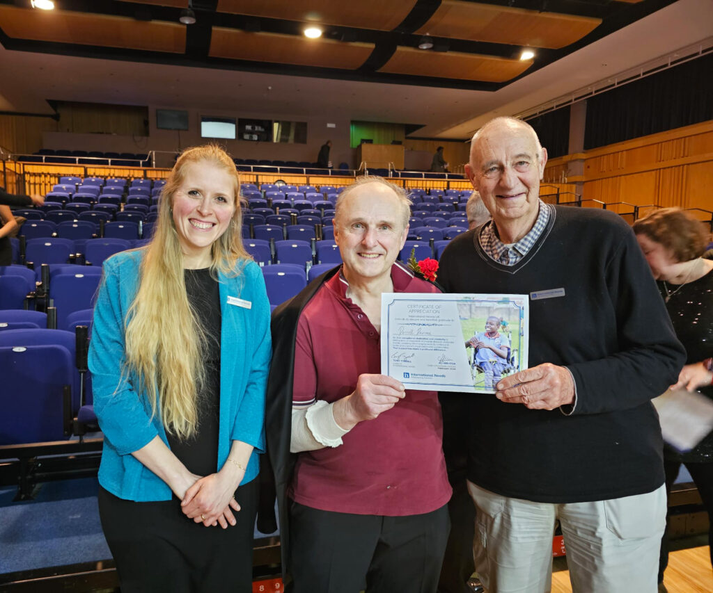 Darrell Davison holds up a certificate from Tony and Ali, that commemorates his fundraising efforts for International Needs