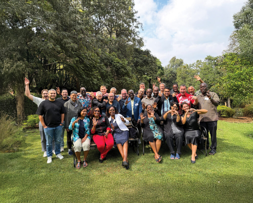 Executive directors from around the world wave and smile together for a photo