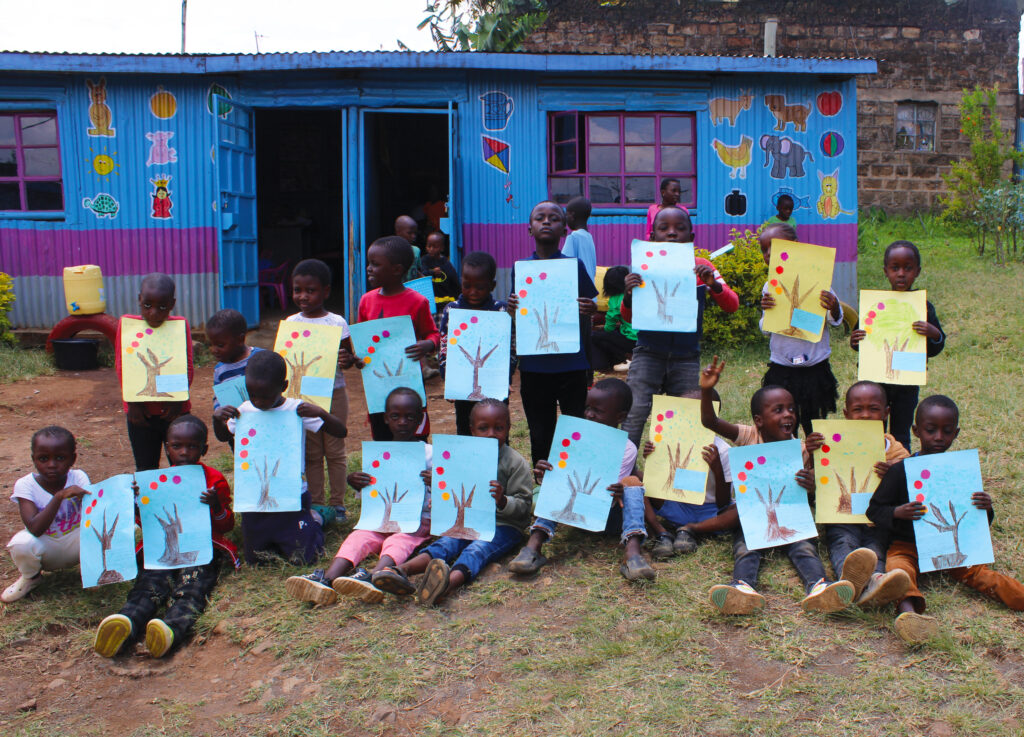 A class of children hold up their drawings