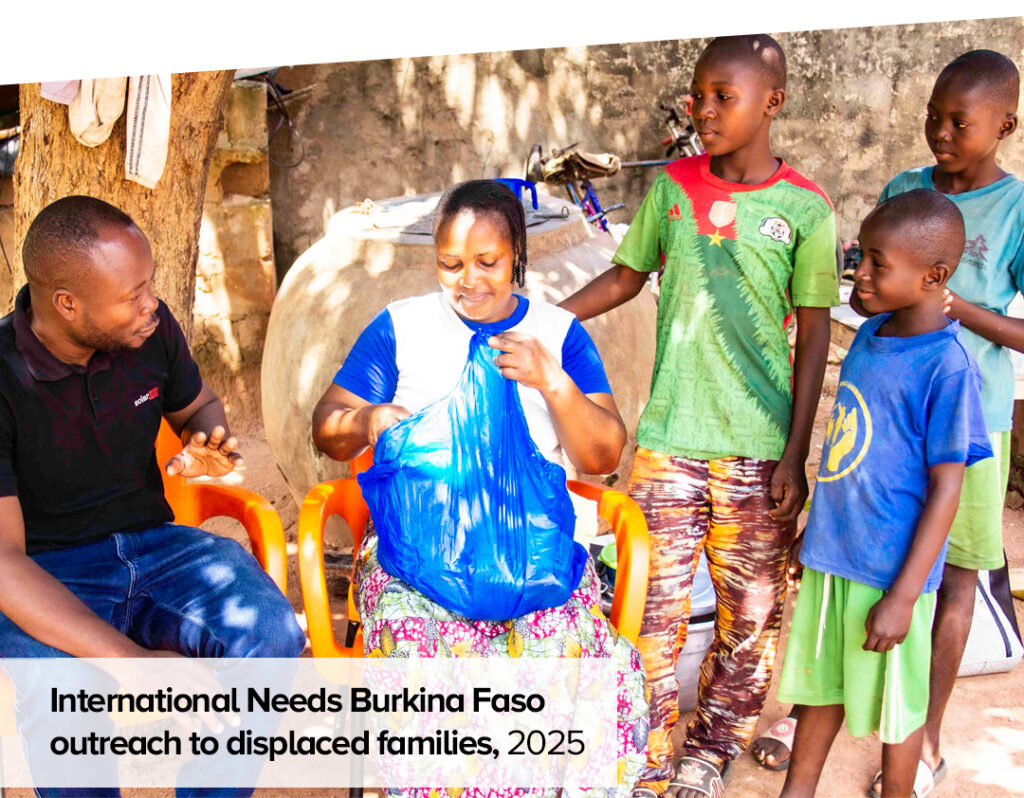 Outreach to displaced families in Burkina Faso, three boys with their mother speak to one of the IN Burkina team