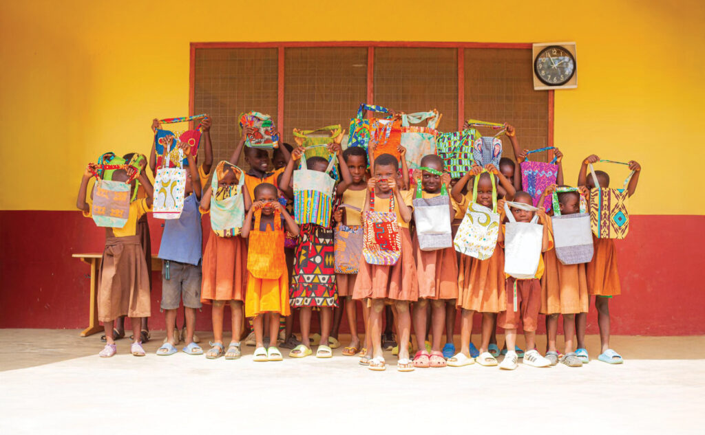 children lift up the colourful patterned bags proudly