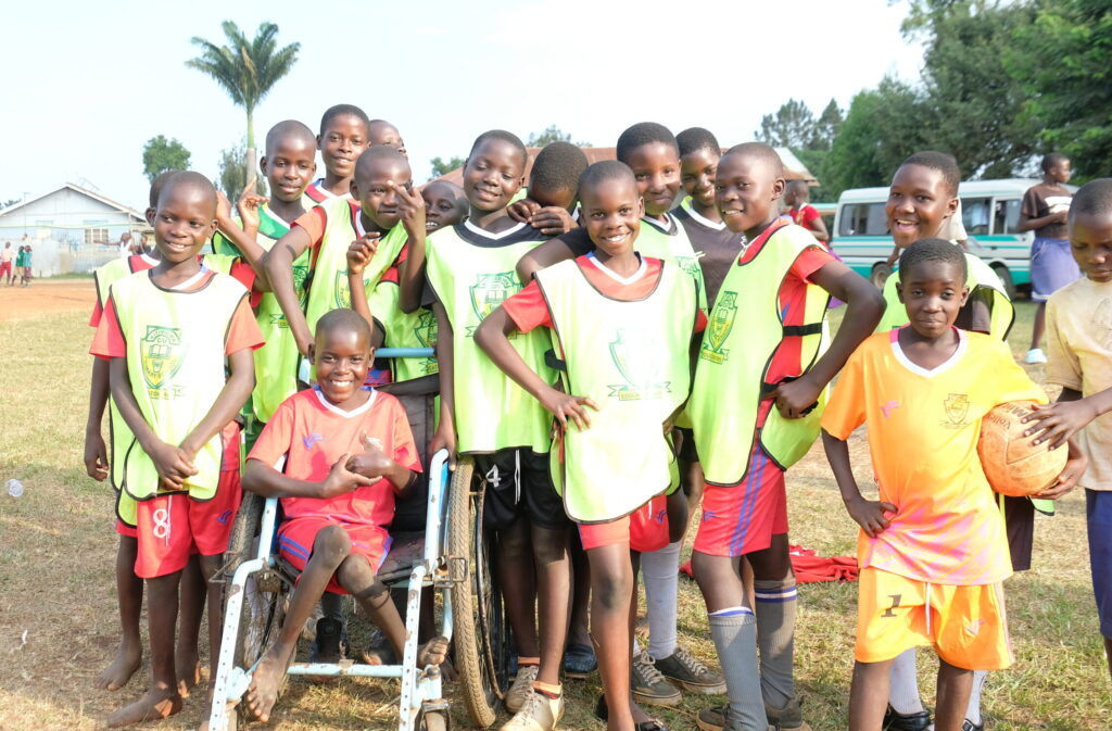 Disability inclusion: a group of friends of all abilities gather together and smile eagerly at a Sports Festival in Uganda