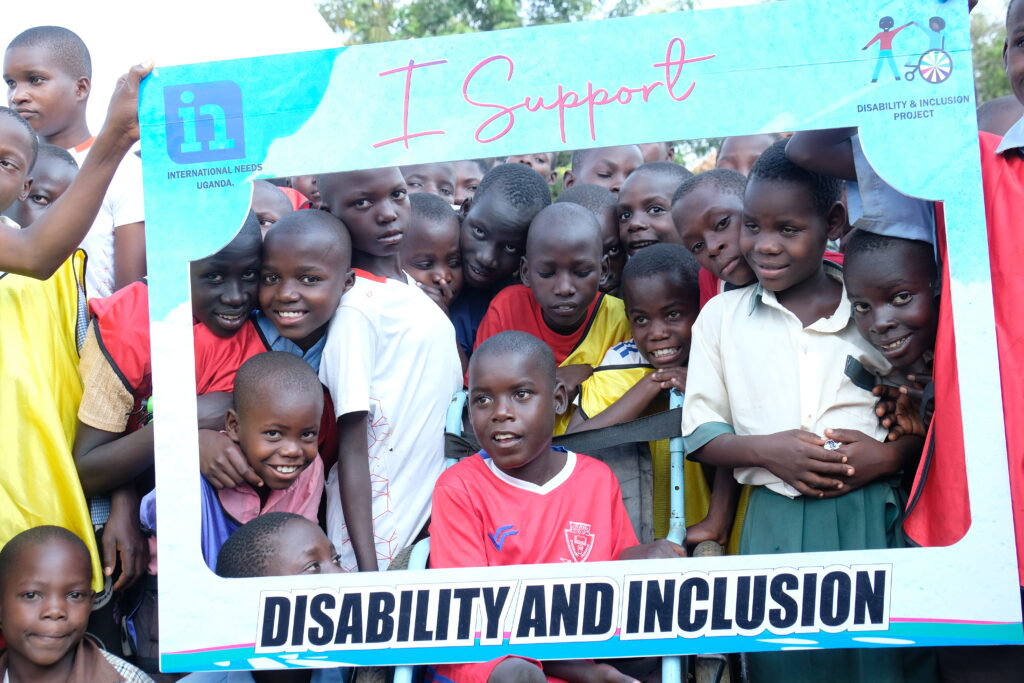 Children smile together holding up a sign that states 'I support disability and inclusion'